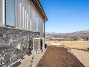 View of property exterior with stone siding, a water and mountain view, and board and batten siding
