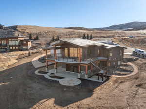 View of front of property with stairs, a patio, a balcony, stone siding, and a mountain view