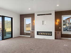 Unfurnished living room featuring healthy amount of natural light, a fireplace, carpet floors, and recessed lighting