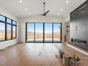 Unfurnished living room with a mountain view, ceiling fan, recessed lighting, plenty of natural light, and a fireplace