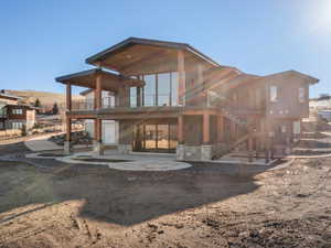 Rear view of property with a balcony, a patio, and stairs