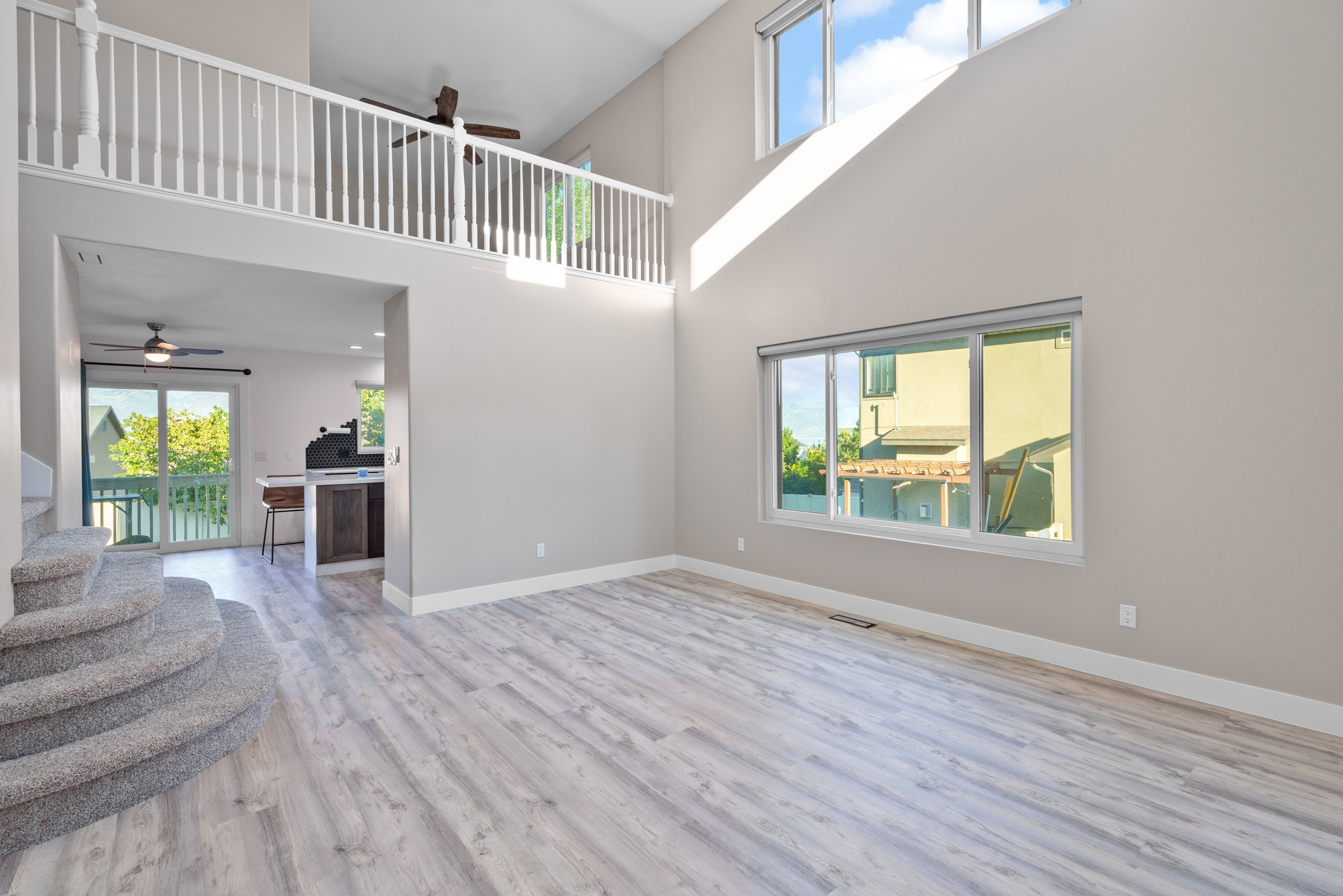 Unfurnished living room with ceiling fan, healthy amount of natural light, light wood finished floors, and stairs