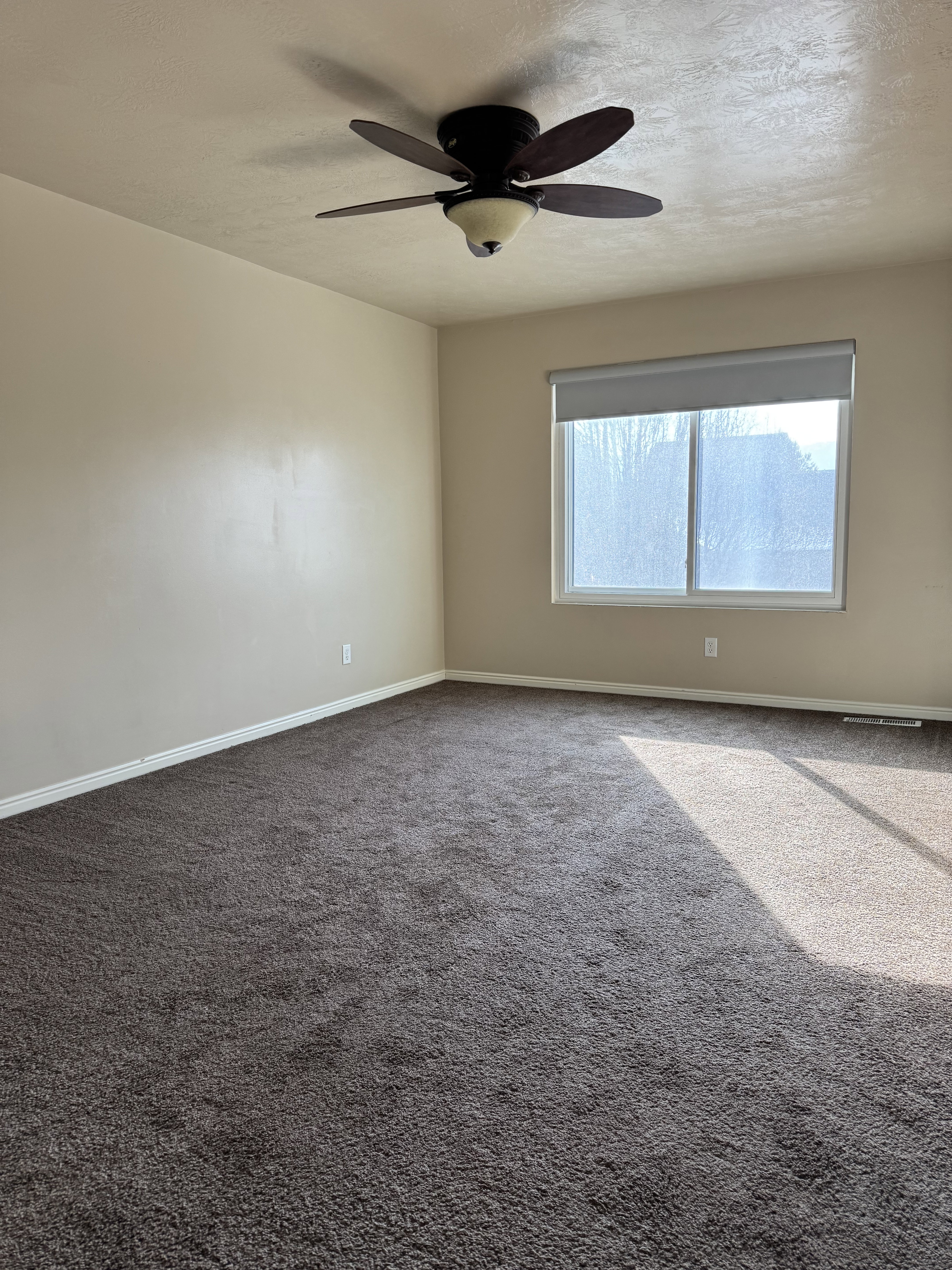 Owners Suite/Master Bedroom featuring dark carpet, a textured ceiling, and a ceiling fan