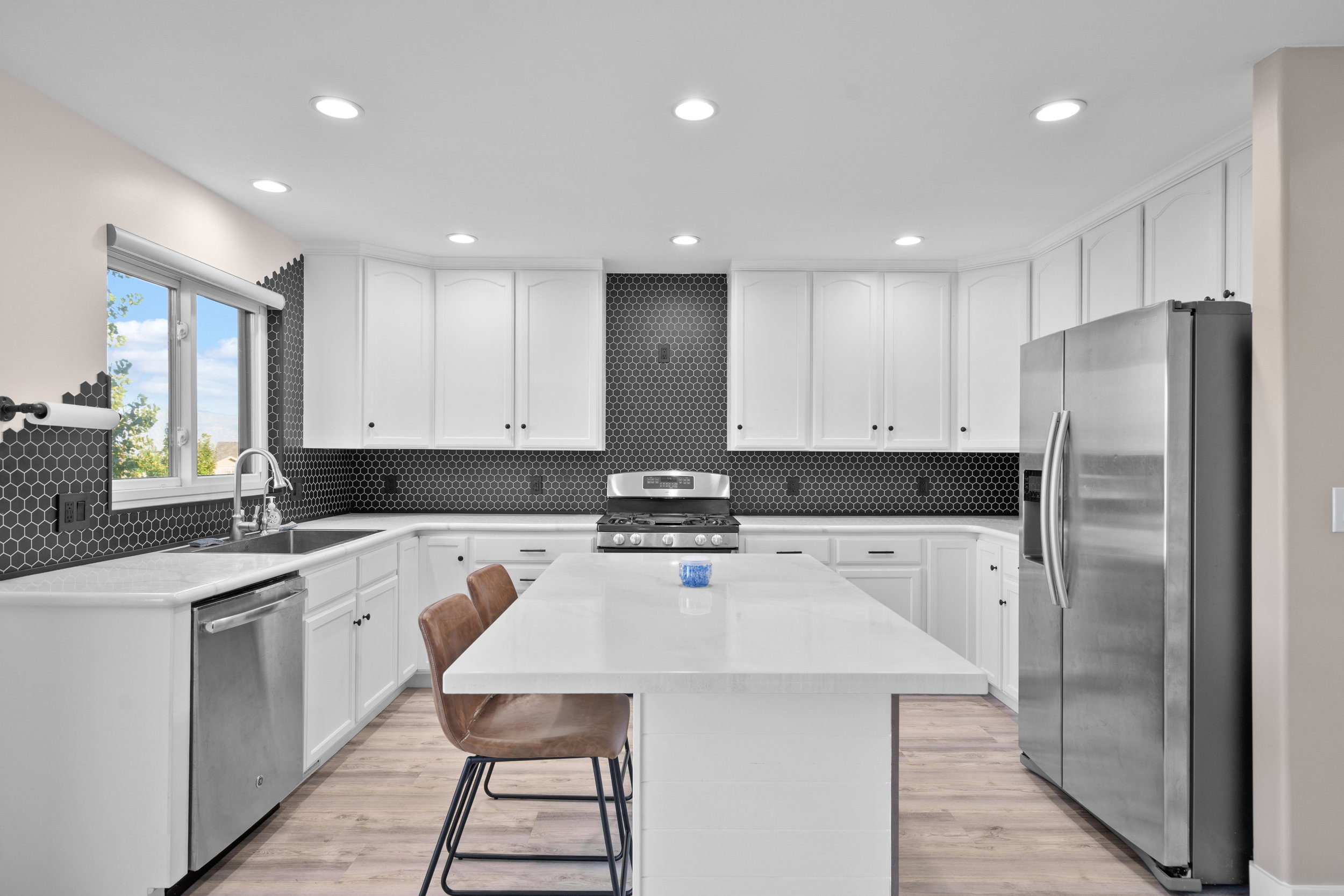 Kitchen with white cabinetry, stainless steel appliances, a breakfast bar area, light stone counters, and recessed lighting