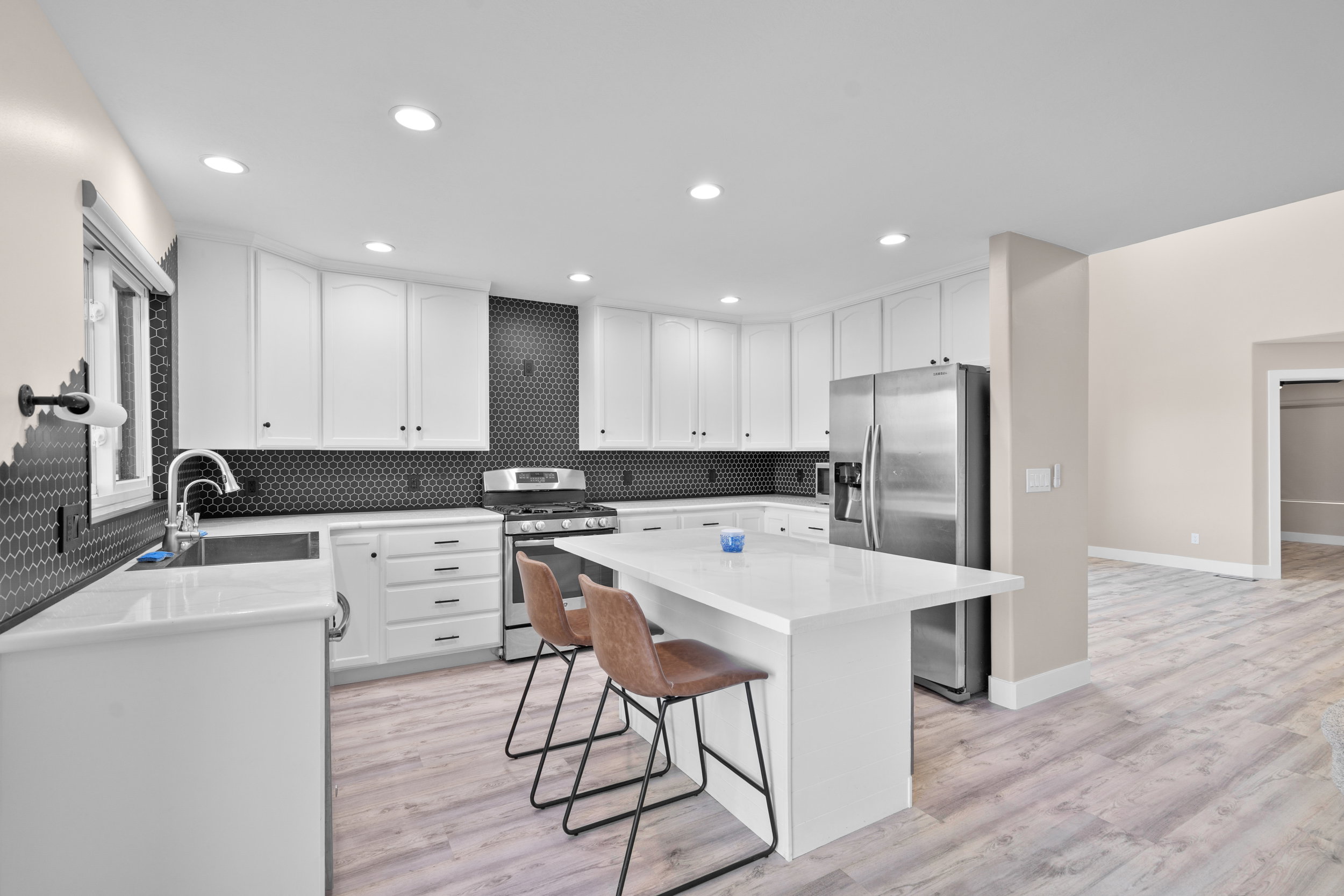 Kitchen featuring stainless steel appliances, a breakfast bar, white cabinets, light stone countertops, and recessed lighting