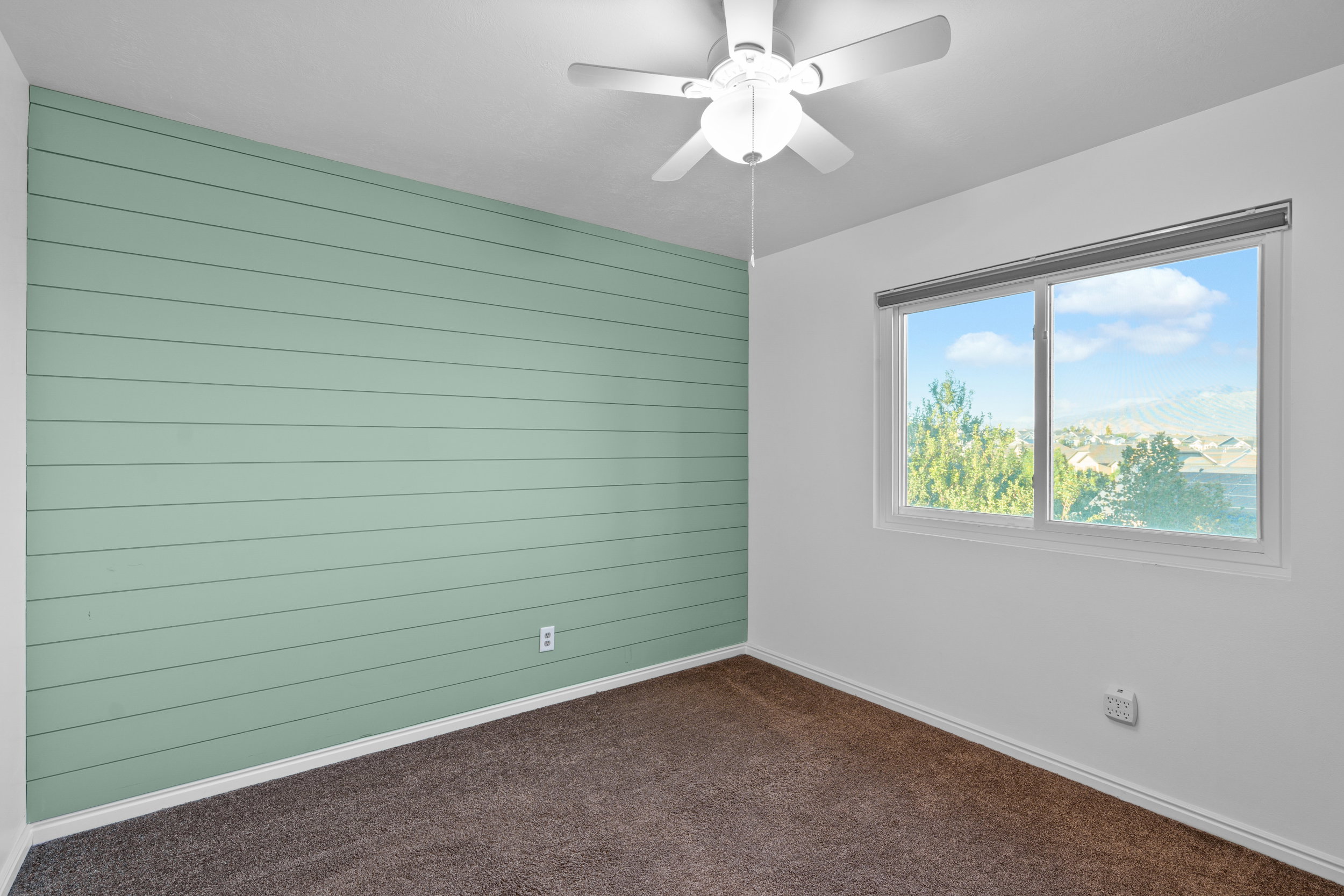 Spare room with wood walls, dark colored carpet, and a ceiling fan