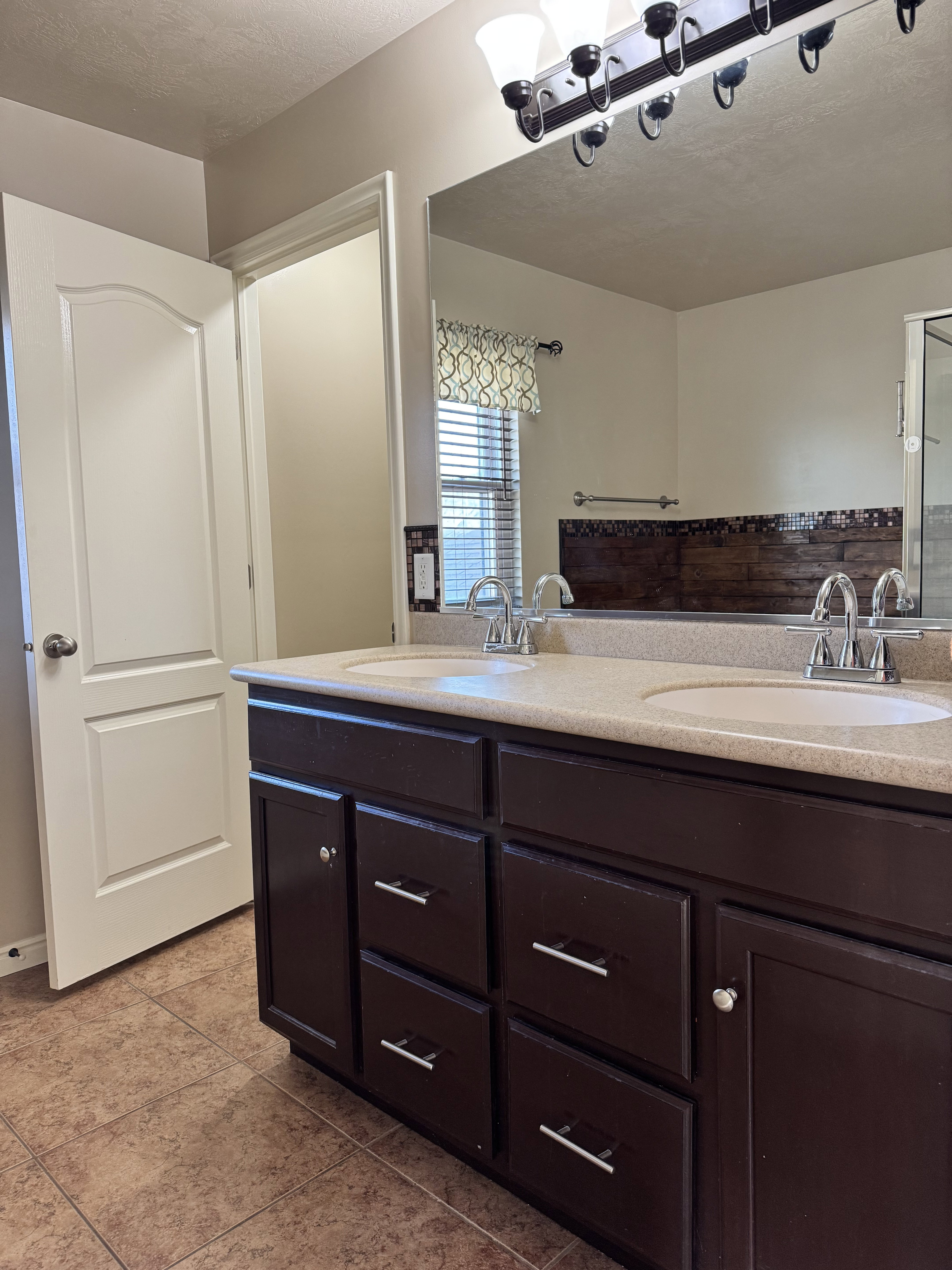 Owners/Master Bathroom with double vanity, a textured ceiling, and light tile patterned flooring
