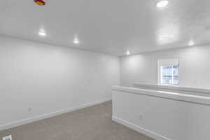 Empty room with light carpet and recessed lighting