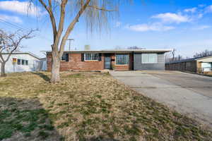 Single story home featuring a front yard, brick siding, and driveway