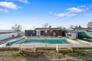 Rear view of house with a fenced backyard, brick siding, a patio area, and a shed