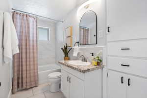 Full bath featuring shower / bath combo, vanity, and a textured ceiling