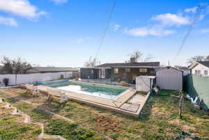 View of pool with a patio area, a fenced backyard, and a storage unit