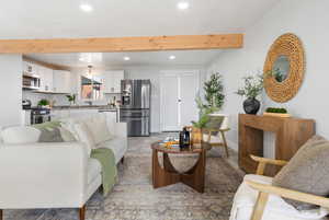 Living room with recessed lighting, beamed ceiling, and light wood-style floors
