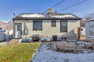 Snow covered back of property featuring a chimney and a shingled roof