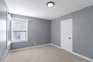 Spare room with light carpet and baseboards