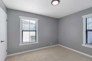Unfurnished room featuring light carpet and baseboards