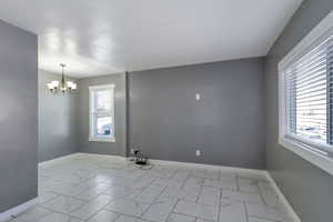 Unfurnished room with light marble finish floors and a chandelier
