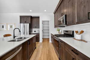 Kitchen featuring dark brown cabinets, appliances with stainless steel finishes, light stone counters, tasteful backsplash, and recessed lighting
