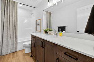 Bathroom featuring shower / bathtub combination with curtain, vanity, and light wood finished floors
