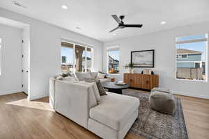 Living room featuring light wood finished floors, a ceiling fan, plenty of natural light, and recessed lighting