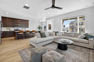 Living area with recessed lighting, light wood-style flooring, ceiling fan, and a chandelier