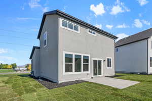 Rear view of property with a yard, a patio area, and stucco siding