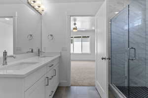 Bathroom featuring light carpet, double vanity, a stall shower, light tile patterned flooring, and ceiling fan