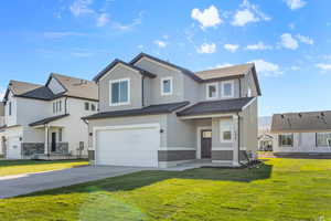View of front facade with a front yard, stucco siding, concrete driveway, an attached garage, and brick siding