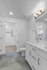 Bathroom featuring double vanity, a spacious closet, and recessed lighting