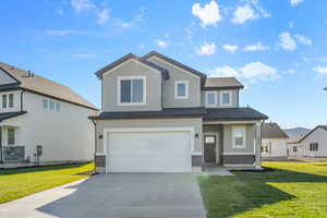 View of front of home with a front yard, stucco siding, driveway, and an attached garage