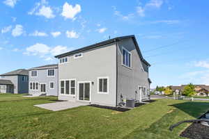 Back of house featuring a yard, a patio area, stucco siding, and a residential view