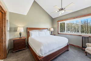Carpeted bedroom featuring lofted ceiling and ceiling fan