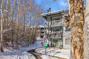 Snow covered rear of property featuring a chimney and a balcony