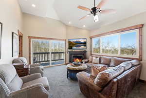 Carpeted living room featuring a glass covered fireplace, plenty of natural light, ceiling fan, high vaulted ceiling, and recessed lighting