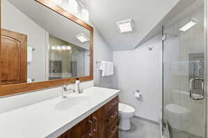 Full bath with vanity, vaulted ceiling, a stall shower, a textured ceiling, and light tile patterned floors