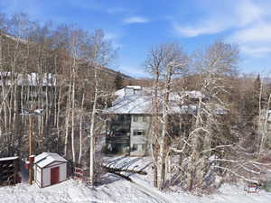 Snow covered property featuring a shed and a chimney