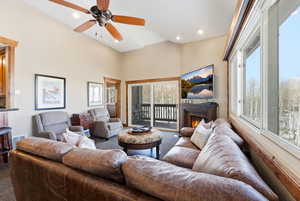 Living area with carpet floors, a warm lit fireplace, ceiling fan, a towering ceiling, and recessed lighting