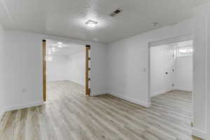Unfurnished room featuring a textured ceiling and light wood-style floors