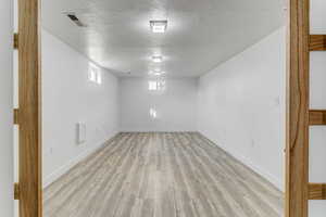 Below grade area featuring a textured ceiling and light wood-style floors