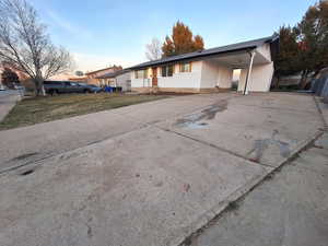 View of front of house featuring concrete driveway, a carport, and a yard