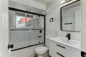 Bathroom with shower / bath combination with glass door, vanity, and a textured ceiling