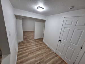 Finished below grade area with a textured ceiling and light wood-type flooring