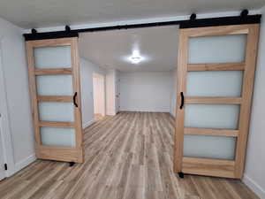 Hall with a barn door, light wood-style floors, and a textured ceiling