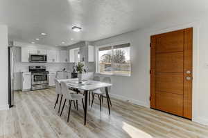 Dining space with recessed lighting, light wood-style flooring, and a textured ceiling