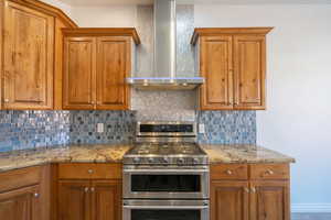 Kitchen with double oven range, wall chimney range hood, and brown cabinets