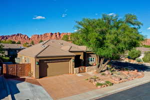 View of front of home with an attached garage, driveway, a gate, a tiled roof, and stone siding