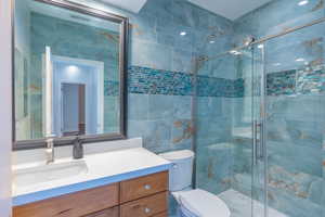 Full bath featuring vanity, a shower stall, and tile walls
