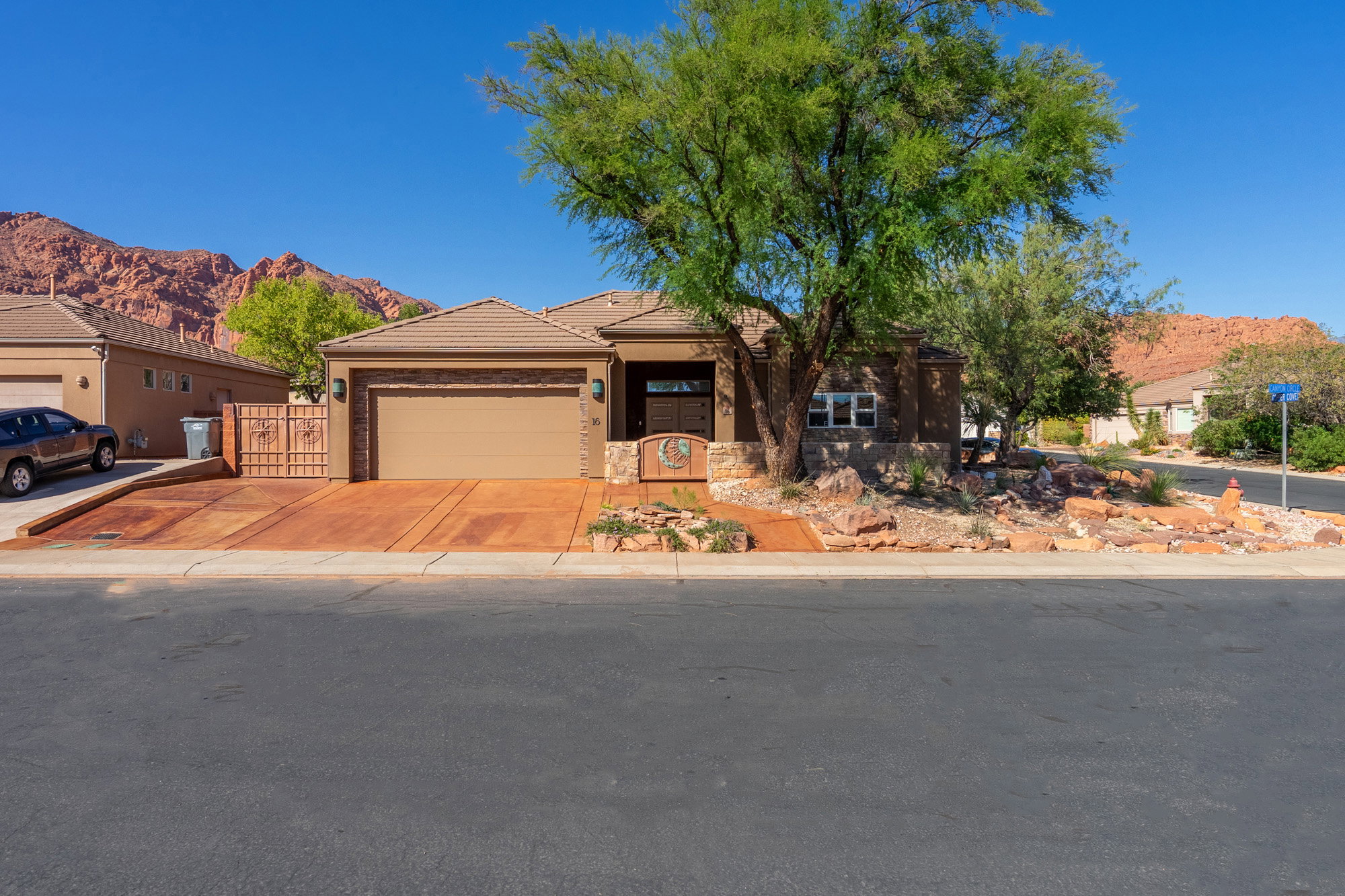 View of front of property featuring a mountain view, a garage, concrete driveway, stone siding, and a tile roof
