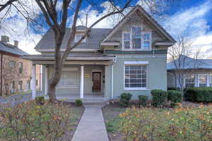 View of front of house featuring a porch, brick siding, and a tile roof