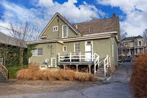 Rear view of house featuring stucco siding, stairway, a chimney, and a deck